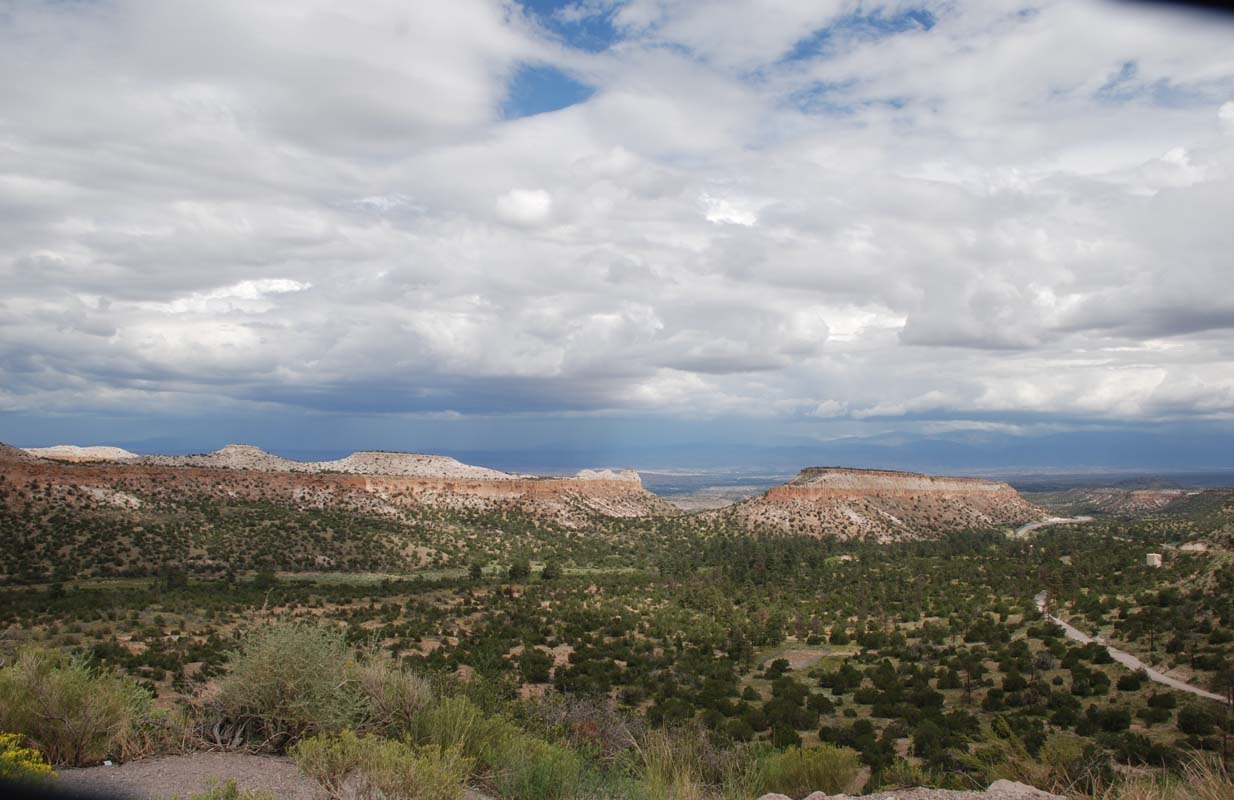 Expansive desert landscape featuring layered mesas under a cloudy sky